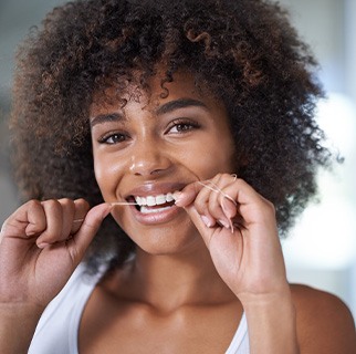 Woman smiling while flossing teeth