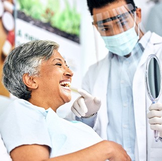 Woman smiling at reflection in handheld mirror