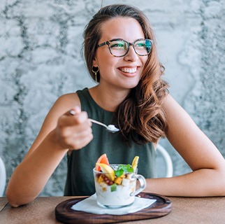 Woman smiling while eating healthy breakfast