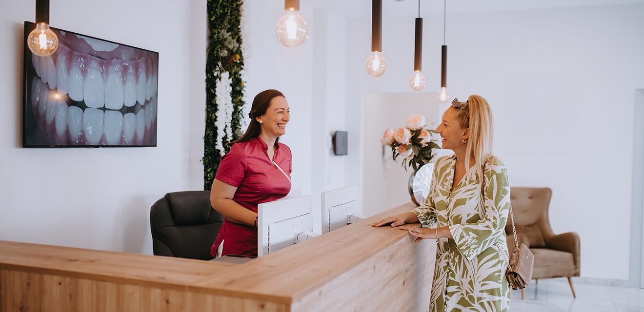 Dental receptionist smiling at patient in lobby