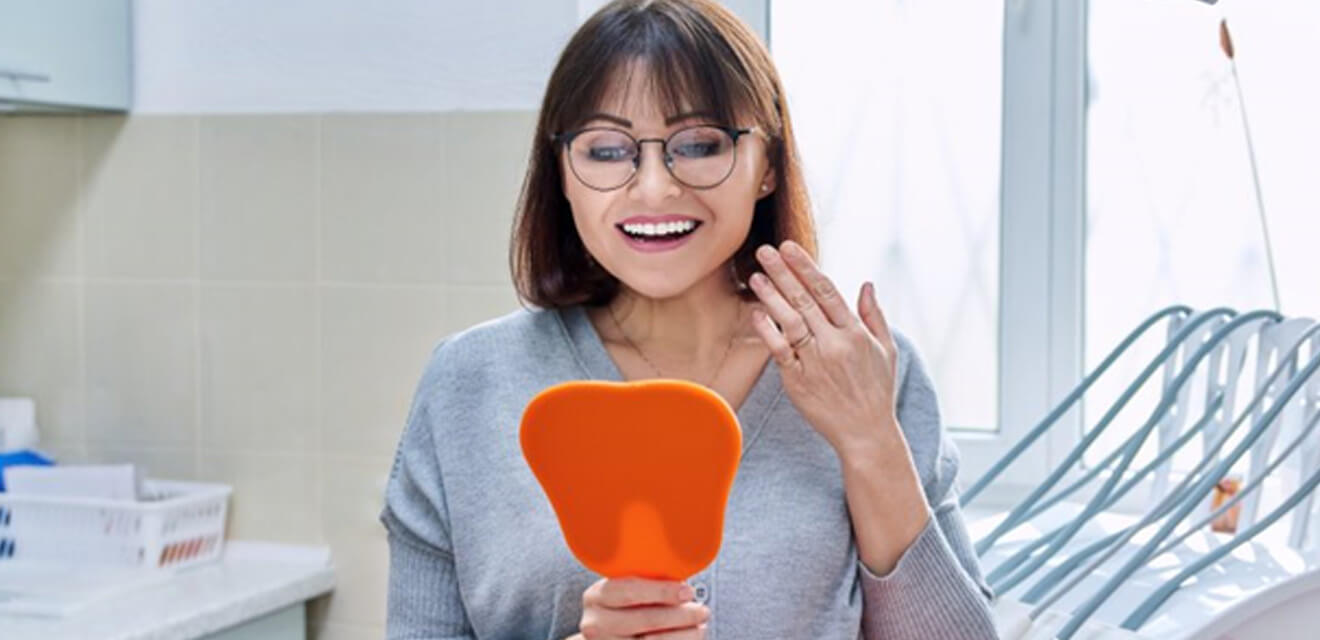 a patient checking her all-on-4 implants with mirror