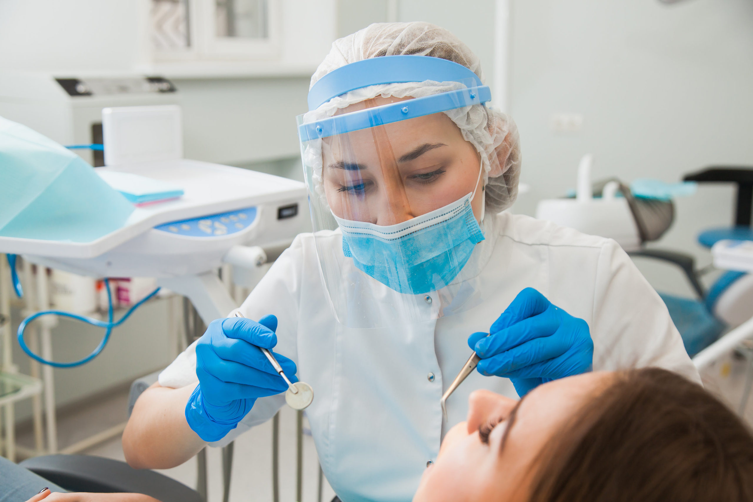 Young female dentist curing patient's teeth filling cavity ...